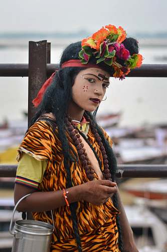 human woman wearing yellow, red ,and orange shirt standing beside black metal fence during daytime person