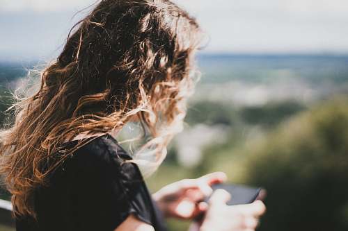 human woman with long curly blonde hair using smartphone person