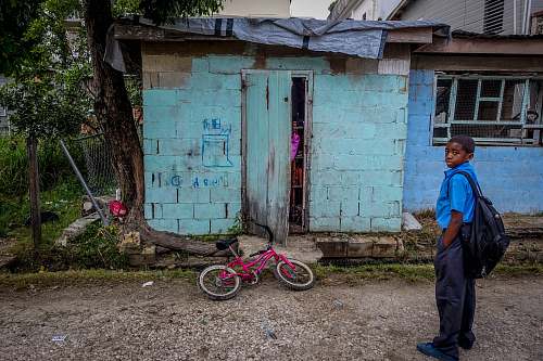human boy standing in front of door near bicycle people