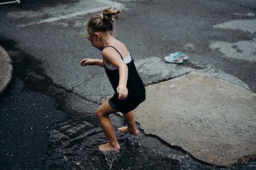people girl jumps in the water surface on asphalt road during daytime human