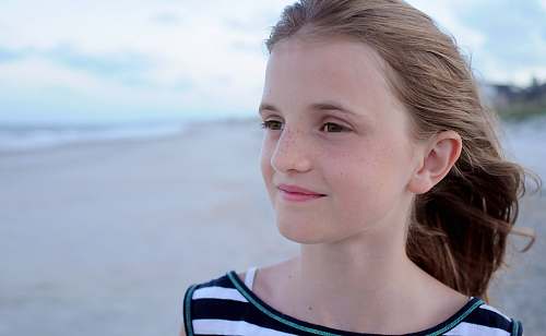 people girl standing at beach wearing white, green, and black striped shirt facing left side human