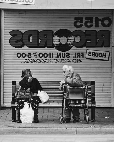 human grayscale man and woman sitting on bench black-and-white