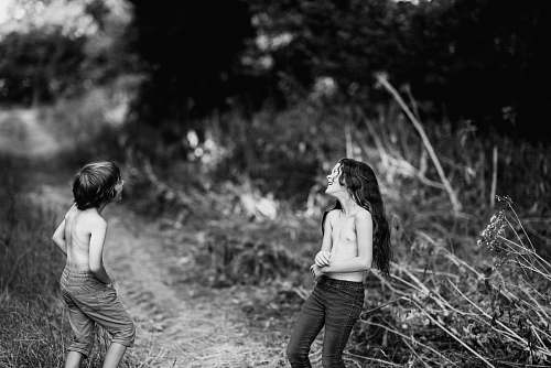 human grayscale photography of girl and boy beside bush black-and-white