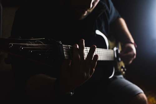 people low light photography of man playing guitar human
