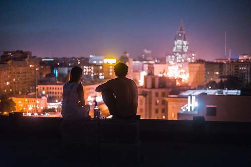 people man and woman chilling on rooftop in front of high-rise buildings human