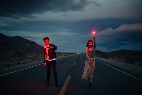 human man and woman holding red flare on yellow line road people