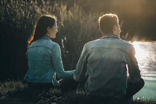 human man and woman sitting near body of water people