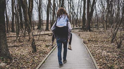 people man carrying a woman on his back in forest path human