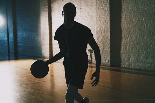 human man dribbling ball in closed basketball court people