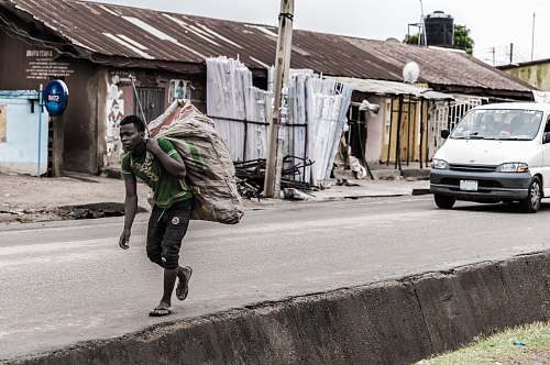 people man holding brown sack beside pave road human