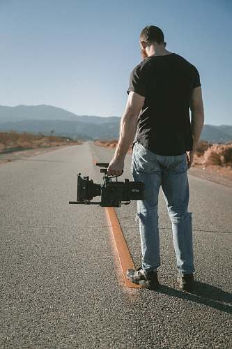 human man holding video camera sanding on road people