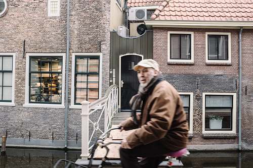 people man in brown jacket sitting beside concrete building human