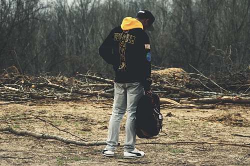 people man in gray denim pants and black hoodie holding bag looking down human