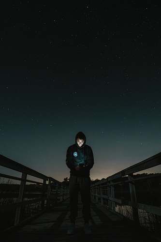 human man in the middle of bridge looking to his phone people