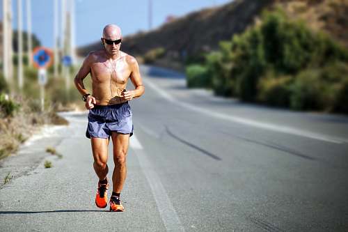 running man jogging while listening using black earphones during day time run
