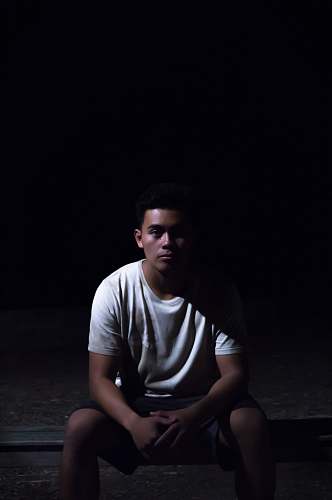 human man sitting on ground with black background people