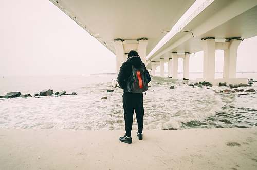 human man standing in front of body of water people