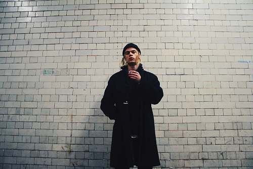 human man standing near gray brick wall people