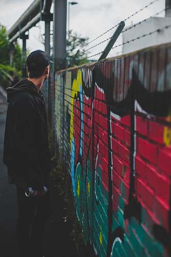 human man standing next to concrete fence holding can people