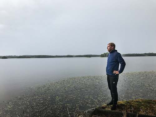 human man standing on cliff near body of water people