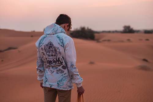 human man standing on desert holding sand during daytime people