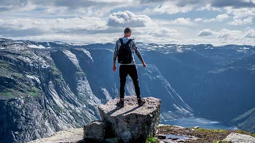 human man standing on edge of cliff mountain