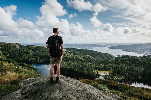 human man standing on mountain beside trees people