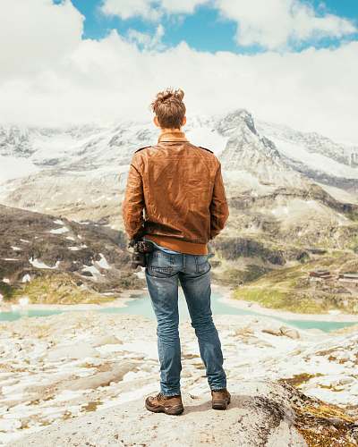 people man standing on rock facing lake and mountains during daytime human