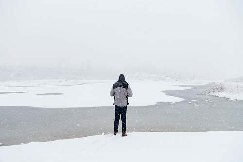 winter man standing on snow field facing river river