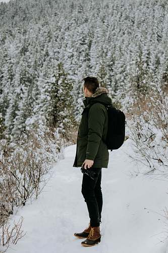 people man standing on snow looking on trees during daytime human
