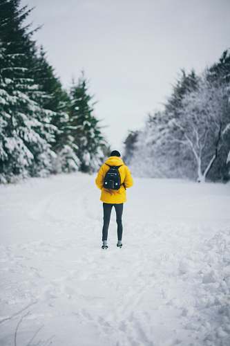 human man standing on snowfield while carrying backpack during daytime people
