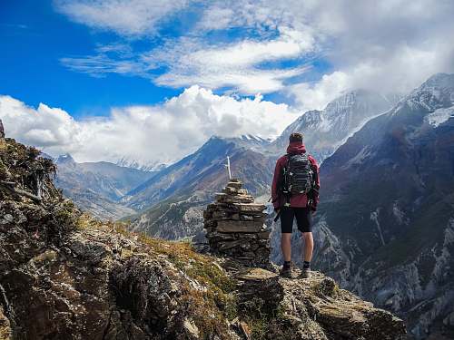 mountain man standing on top of mountain beside cairn stones mountain range