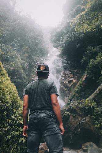 human man standing while staring on water falls people