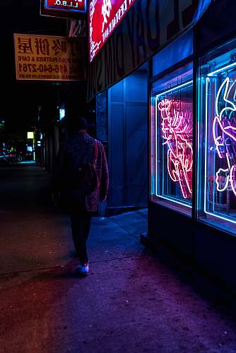 people man walking beside neon-lighted store taken at nigthttime human