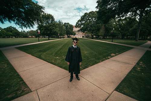 people man wearing academic gown standing on green field human