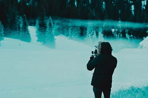 human man wearing black hoodie jacket while standing on snow covered pathway people