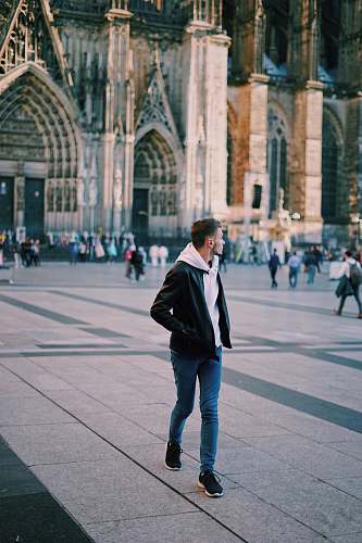 people man wearing black jacket and blue jeans walking on street human