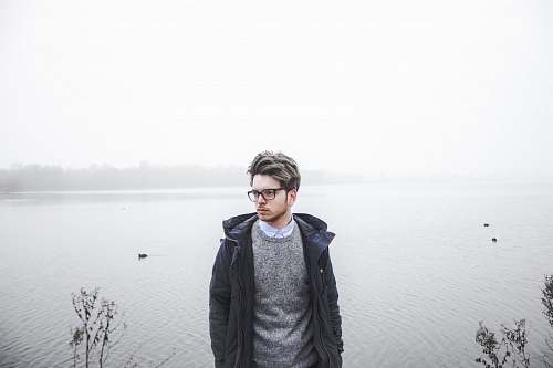 people man wearing black jacket standing near body of water human