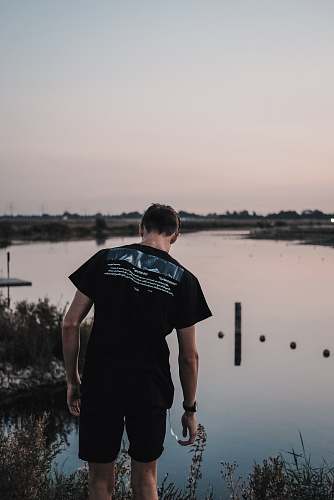 human man wearing black shirt near lake people