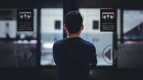 human man wearing blue top facing glass door people