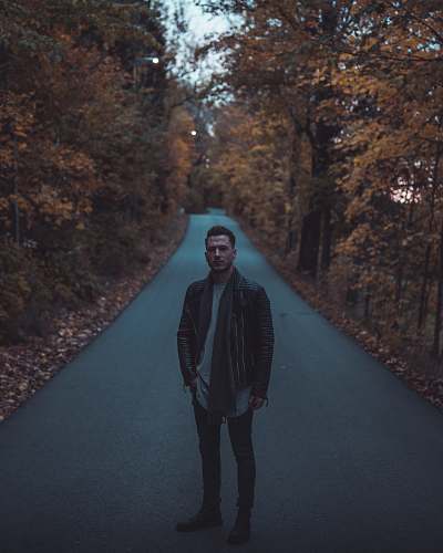 people man wearing brown leather jacket standing on road human