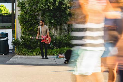 human man wearing brown shirt playing guitar people