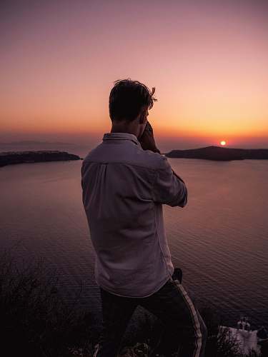 human man wearing dress shirt standing on cliff during golden hour people