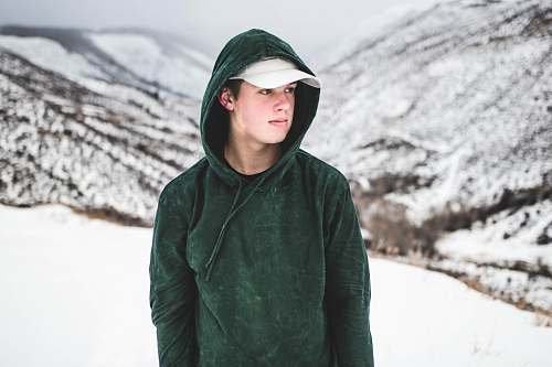 human man wearing green drawstring hoodie and white cap people