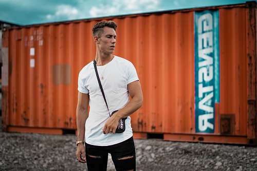people man wearing white t-shirt near orange intermodal container human