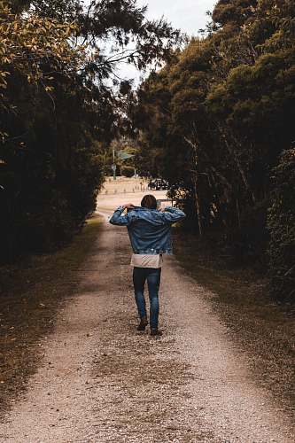 human person holding denim jacket while walking road