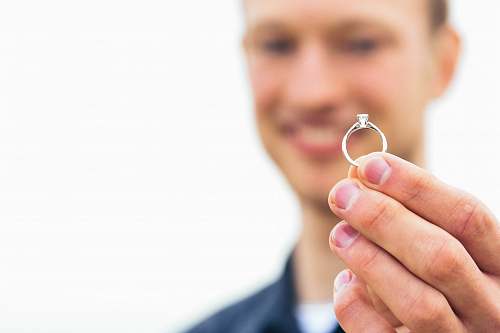 people person holding silver-colored clear gemstone encrusted ring human