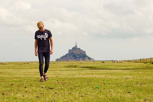 people person in b lack crew-neck shirt walking on green path grass field