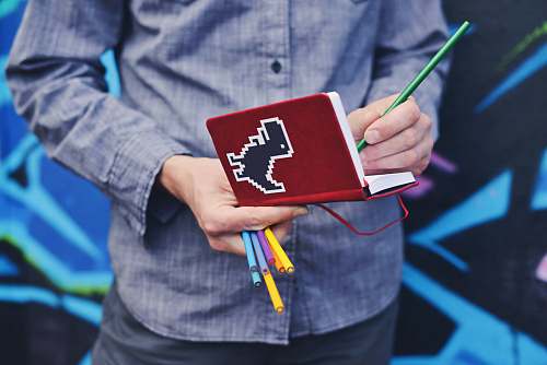 people person in blue dress shirt holding red book and colored pens human