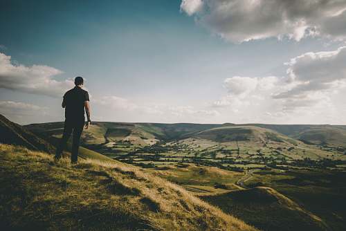 human person standing on hill during cloudy daytime people